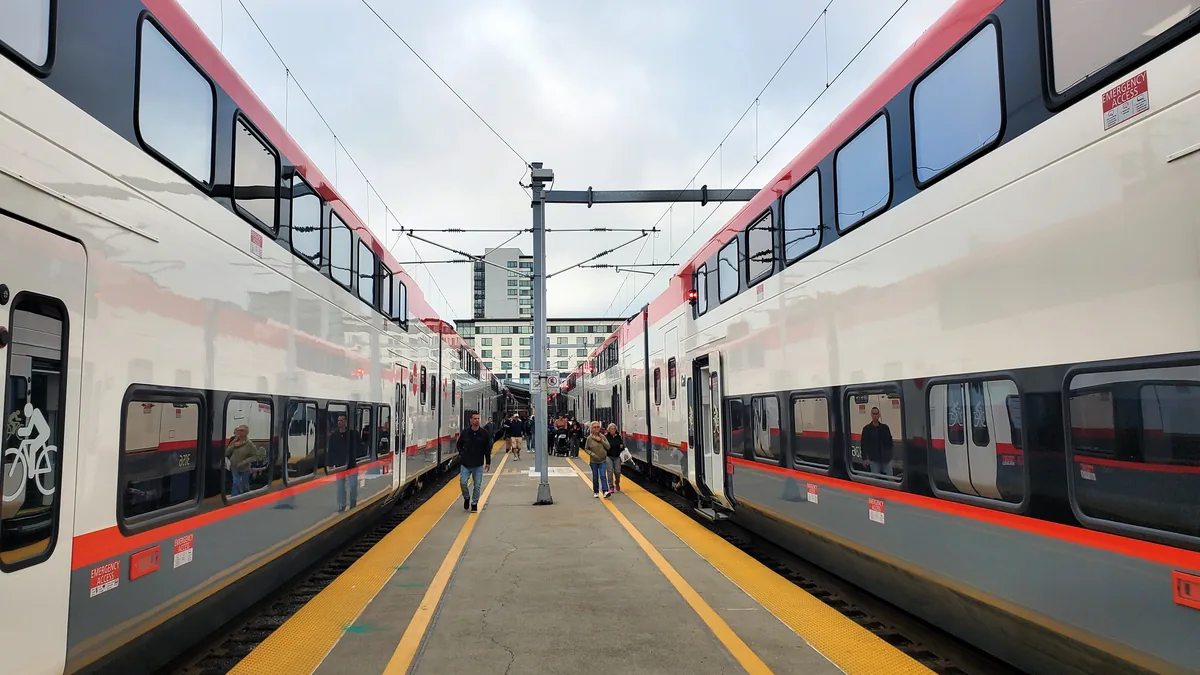 Two Caltrain trains on either side of a platform at San Francisco's 4th and King terminal, with passengers walking.